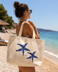 Woman on a beach holding a tote bag with starfish designs